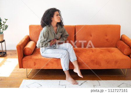 woman at home dealing with abdominal discomfort touching aching belly woman at home dealing with abdominal discomfort touching aching belly 112727181
