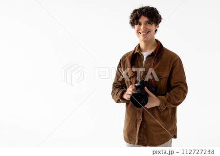 Smiling young male photographer holding DSLR camera 112727238