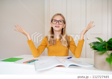 Confused teen girl studying with books at home and raising her hands 112727485