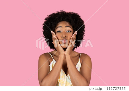 Playful African American woman with curly hair making a funny face with puffed cheeks 112727535