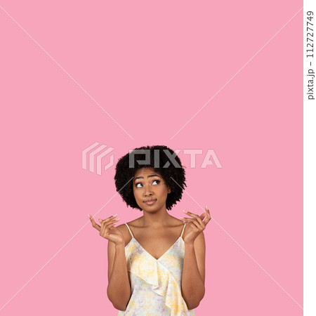 Uncertain African-American woman with fingers crossed, looking upwards and hoping for the best Uncertain African-American woman with fingers crossed, looking upwards and hoping for the best 112727749