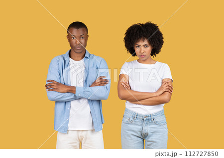 Unsatisfied young man and woman in casual clothing standing with arms crossed Unsatisfied young man and woman in casual clothing standing with arms crossed 112727850