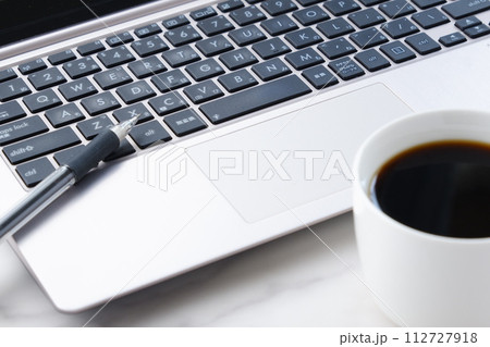 コーヒーを飲みながらノートパソコンでデスクワークをしているイメージ 112727918