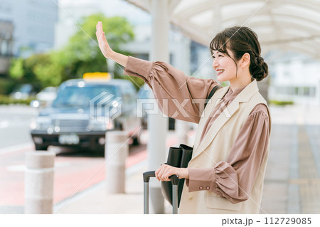 タクシー乗り場で手を挙げてタクシーを呼び止める若いアジア人ビジネスウーマン(出張・転勤) タクシー乗り場で手を挙げてタクシーを呼び止める若いアジア人ビジネスウーマン(出張・転勤) 112729085