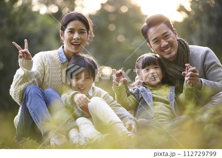 outdoor portrait of a happy young asian family with two children sitting outdoor portrait of a happy young asian family with two children sitting 112729799