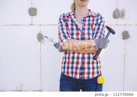 The female worker stands in front of a wall insulated with foam plastic 112730066