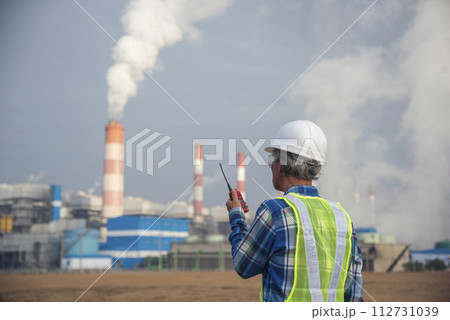 Senior Electrician engineer man hand holding red Walkie talkie communicate wear White hardhat at Power stations manufacturing electrical plant. Technician worker blue hard hat helmet Engineer industry Senior Electrician engineer man hand holding red Walkie talkie communicate wear White hardhat at Power stations manufacturing electrical plant. Technician worker blue hard hat helmet Engineer industry 112731039
