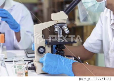 Scientist man look into Microscope research in science laboratory. Asian scientist looking equipment laboratory chemistry labs. Covid-19 coronavirus biochemistry research experiment vaccine concept Scientist man look into Microscope research in science laboratory. Asian scientist looking equipment laboratory chemistry labs. Covid-19 coronavirus biochemistry research experiment vaccine concept 112731081