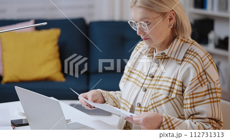A woman in her 50s is working on her laptop from home, a financial analyst, freelancer 112731313