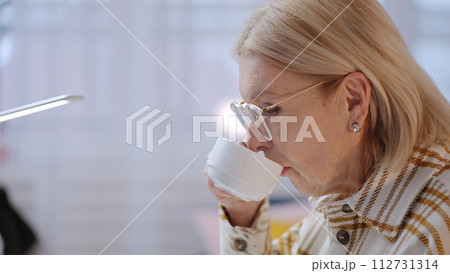 A senior woman is enjoying a cup of coffee while working at home as an IT specialist 112731314