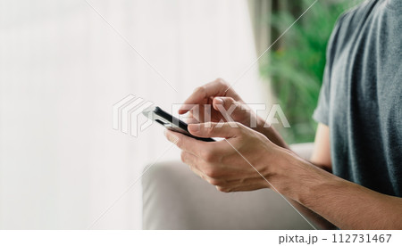 A man is holding a cell phone and is looking at it 112731467