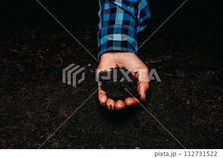 The farmer carefully crushes the fertile black soil in his hands, enjoying its softness. The farmer's hands hold a handful of earth and tear it apart with his fingers. Earth in hands. The farmer carefully crushes the fertile black soil in his hands, enjoying its softness. The farmer's hands hold a handful of earth and tear it apart with his fingers. Earth in hands. 112731522