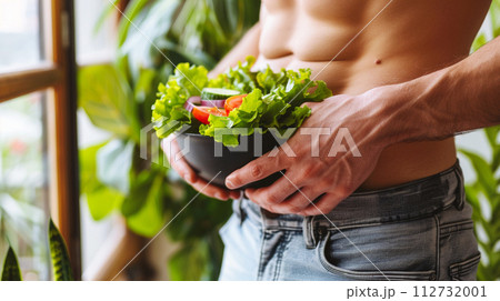 お腹の前で野菜を持つ男性　ダイエットイメージ 112732001