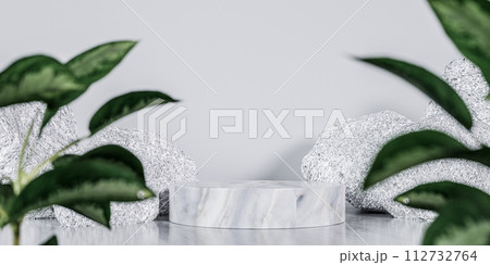 Product placement. Display Stand marble podium surrounded by white stones and lush green leaves. showcasing luxury products or cosmetics with blend of nature and sophistication 112732764