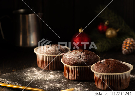 chocolate muffins with powdered sugar on top on a black background. Christmas decoration . Still life close up. Food photo. chocolate muffins with powdered sugar on top on a black background. Christmas decoration . Still life close up. Food photo. 112734244