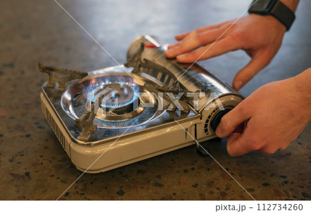 Active lifestyle. A man's hand turns on a portable gas stove. An alternative source for cooking at home during a power outage. 112734260