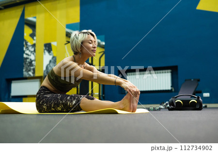a slender athletic woman in the gym is beautifully engaged in yoga exercises on a mat 112734902