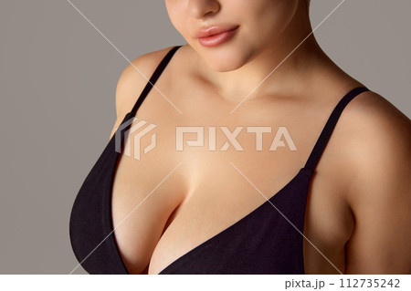 Cropped portrait of woman, plus size model with well-kept, toned skin on neckline zone against grey studio background. Cropped portrait of woman, plus size model with well-kept, toned skin on neckline zone against grey studio background. 112735242