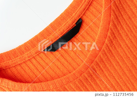 A close-up of the orange ribbed sweater's neckline, highlighting the texture and quality of the fabric. A close-up of the orange ribbed sweater's neckline, highlighting the texture and quality of the fabric. 112735456