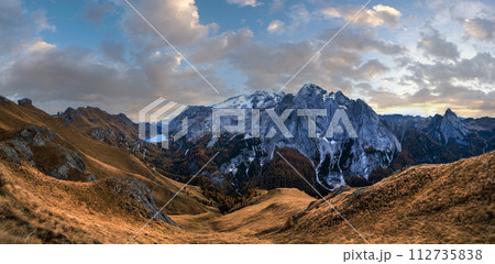 Autumn Dolomites mountain scene from hiking path betwen Pordoi Pass and Fedaia Lake, Italy. Snowy Marmolada Glacier and Fedaia Lake in far. 112735838