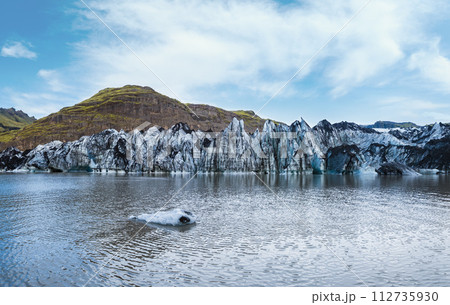 Soheimajokull picturesque glacier in southern Iceland. The tongue of this glacier slides from the volcano Katla. Beautiful glacial lake lagoon with blocks of ice and surrounding mountains. Soheimajokull picturesque glacier in southern Iceland. The tongue of this glacier slides from the volcano Katla. Beautiful glacial lake lagoon with blocks of ice and surrounding mountains. 112735930