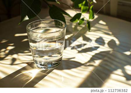 Tranquil scene with a glass of water bathed in sunlight 112736382