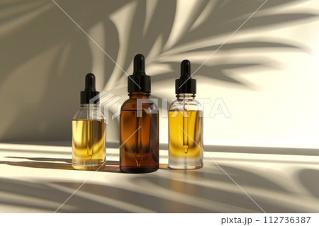 Three elegant dropper bottles bask in soft light, casting sleek shadows Three elegant dropper bottles bask in soft light, casting sleek shadows 112736387