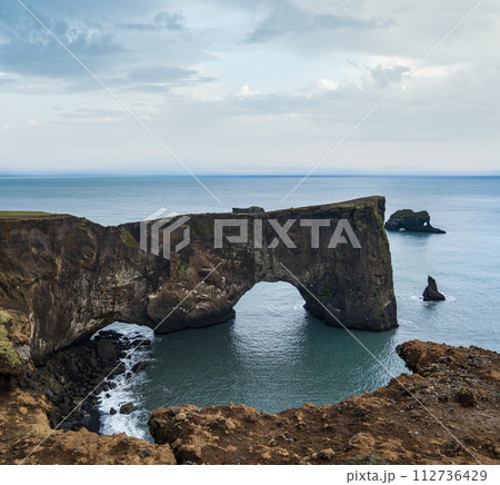 Picturesque autumn evening view to Dyrholaey coast cliffs and rocky arch, Vik, South Iceland. Picturesque autumn evening view to Dyrholaey coast cliffs and rocky arch, Vik, South Iceland. 112736429