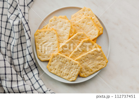 Golden Baked Crackers on plate on a White kitchen table. Top view. 112737451