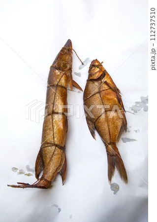 Smoked freshwater pike and common bream fish for home use on white paper.. 112737510