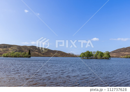 Nestled in a Scottish loch, an island bursts with greenery, home to elusive red deer 112737628