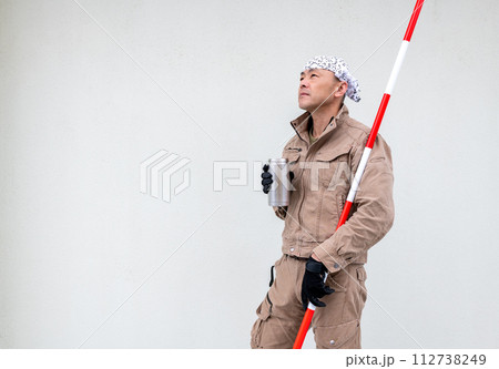 測量ポールを小脇に抱えながら水筒で水分補給をする土木系の男性 測量ポールを小脇に抱えながら水筒で水分補給をする土木系の男性 112738249