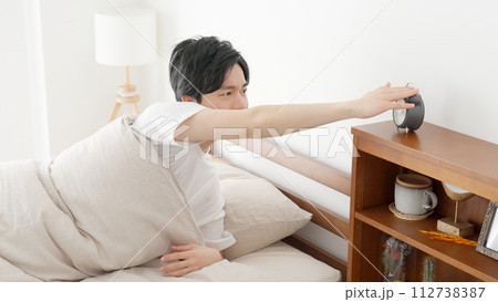 目覚まし時計を止める男性 目覚まし時計を止める男性 112738387