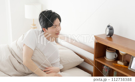 目覚まし時計の時間を確認する男性 112738388