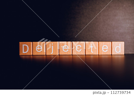 Wooden blocks form the text "Dejected" against a black background. 112739734