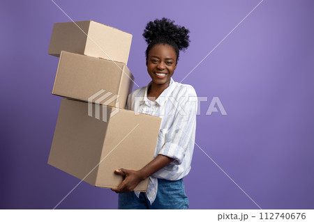 Dark-skinned young woman with boxes in hands looking contented Dark-skinned young woman with boxes in hands looking contented 112740676