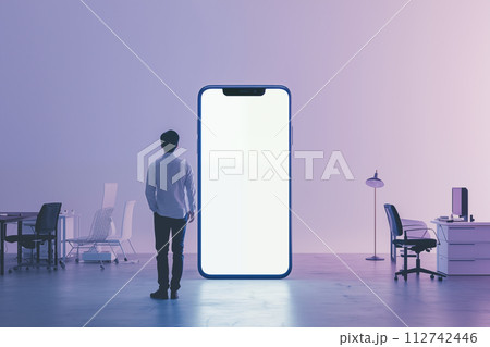 巨大スマートフォンとオフィス環境を見つめる男性 112742446