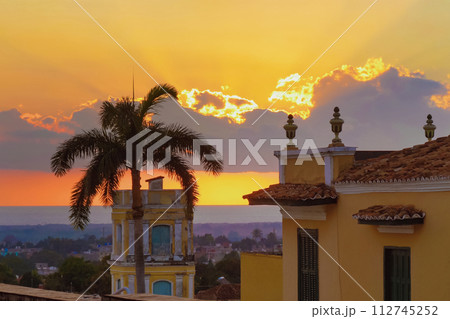 Swaying palm tree leaves against a golden sunset of sea. Swaying palm tree leaves against a golden sunset of sea. 112745252