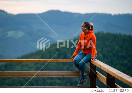 a young girl sits on a wooden handrail. a young girl sits on a wooden handrail. 112748270