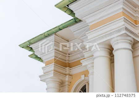 Classical portico with yellow and white details under green roof 112748375