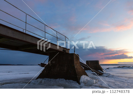 Old broken pier is under sunset sky on a winter evening Old broken pier is under sunset sky on a winter evening 112748378
