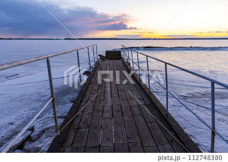 An old pier with wooden flooring is under sunset sky An old pier with wooden flooring is under sunset sky 112748380