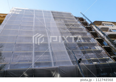 Gray safety net around a large city house facade during reconstruction, grey protective coating Gray safety net around a large city house facade during reconstruction, grey protective coating 112748568