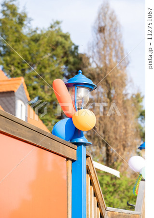 Electric blue lamp post adorned with colorful balloons under the sky Electric blue lamp post adorned with colorful balloons under the sky 112751067
