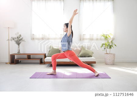逆光の美しいリビングでヨガをする女性全身　戦士のポーズ 112751646