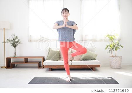 逆光の美しいリビングでストレッチや運動をする女性全身 木のポーズヴルクシャーサナ 逆光の美しいリビングでストレッチや運動をする女性全身 木のポーズヴルクシャーサナ 112751650