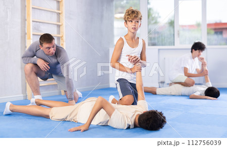 Diligent preteen student twisting his opponent's arm on the floor Diligent preteen student twisting his opponent's arm on the floor 112756039