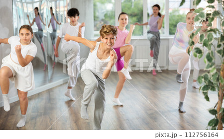 Group of teenagers learn to dance hip-hop and other modern dances in spacious dance studio Group of teenagers learn to dance hip-hop and other modern dances in spacious dance studio 112756164