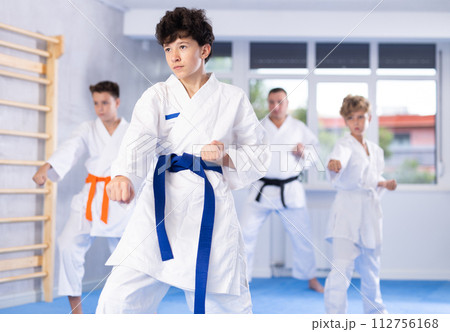 Preteen school childs together trying martial moves in karate class on tatami Preteen school childs together trying martial moves in karate class on tatami 112756168