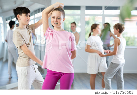 Girl dances Latin dance with male boy teen partner during choreography lesson 112756503